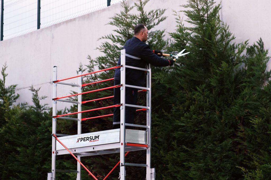 Trabajador sobre andamio Brandon realizando labores de jardinería