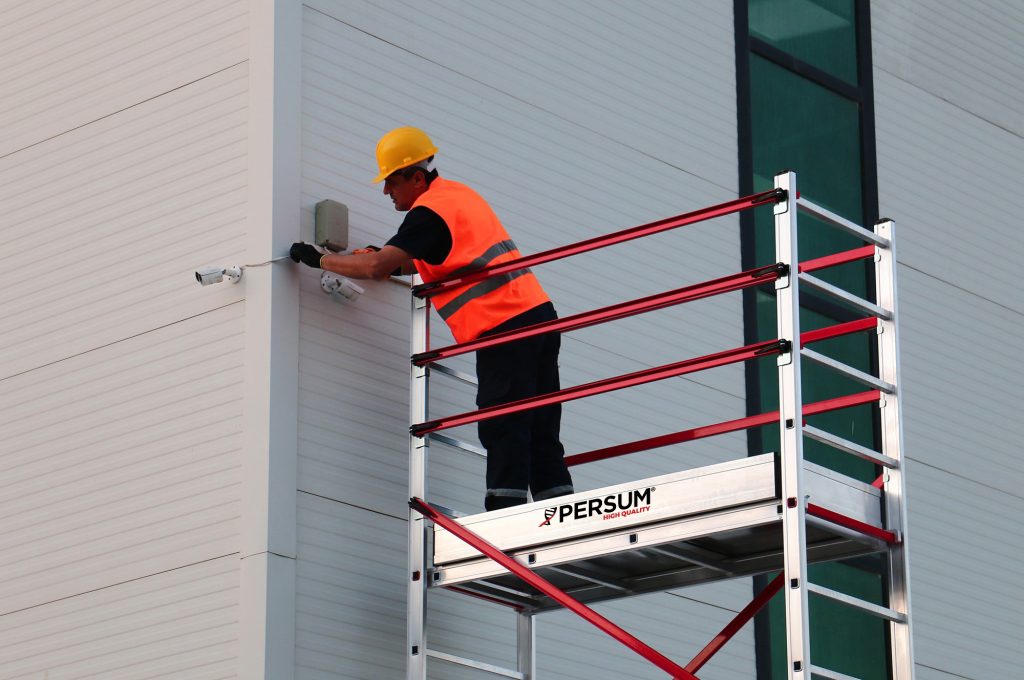 vista de cerca de un operario sobre andamio teletower colocando unas cámaras de seguridad