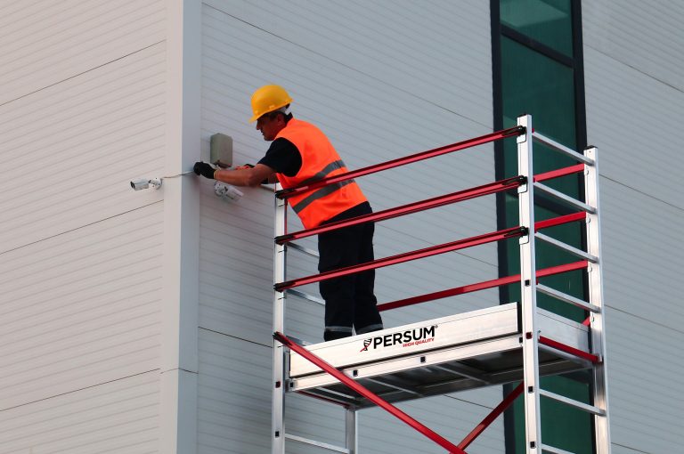 vista de cerca de un operario sobre andamio teletower colocando unas cámaras de seguridad