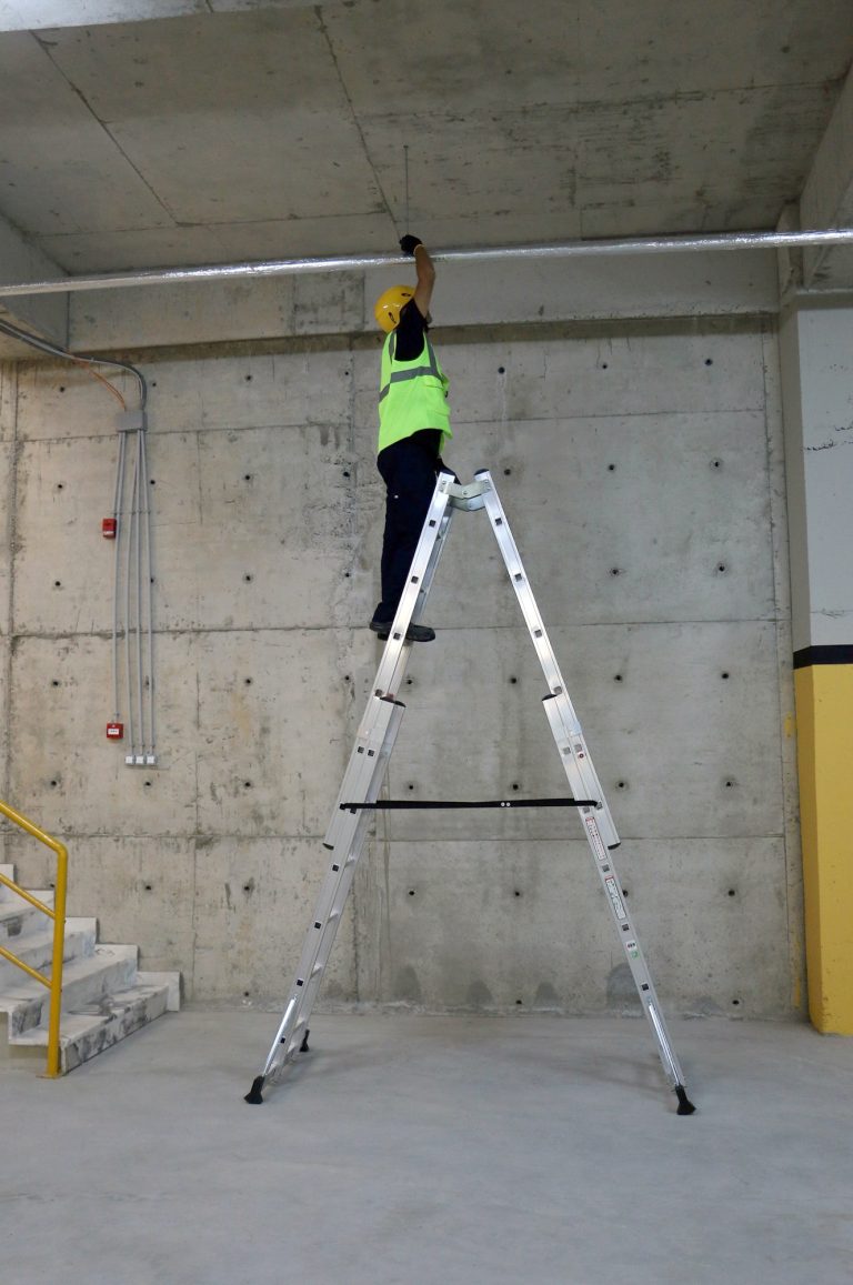Operario sobre escalera Iteem Pro Telescópica revisando anclaje al techo
