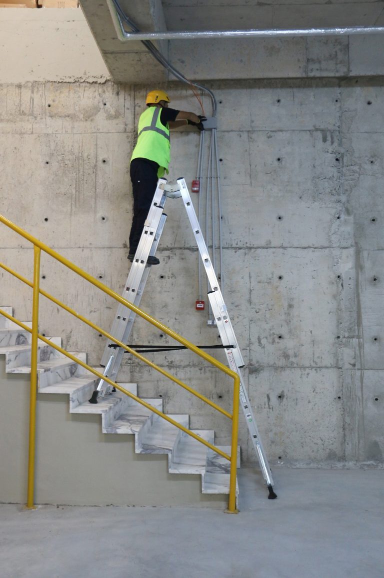 Operario sobre escalera Iteem Pro Telescópica revisando anclaje al techo