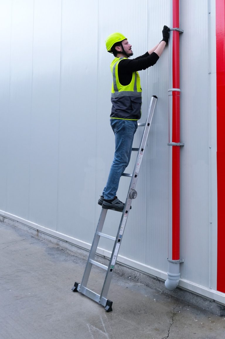Trabajador asegurando un bajante subido a la escalera Crono