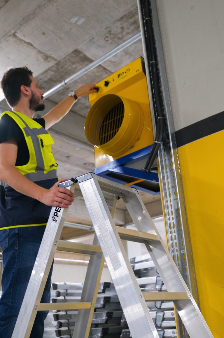 Operario encendiendo un extractor subido a la escalera Duplex