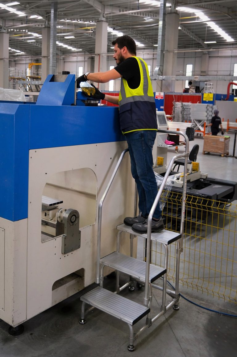 Operario sobre taburete Kamet poniendo a punto una máquina