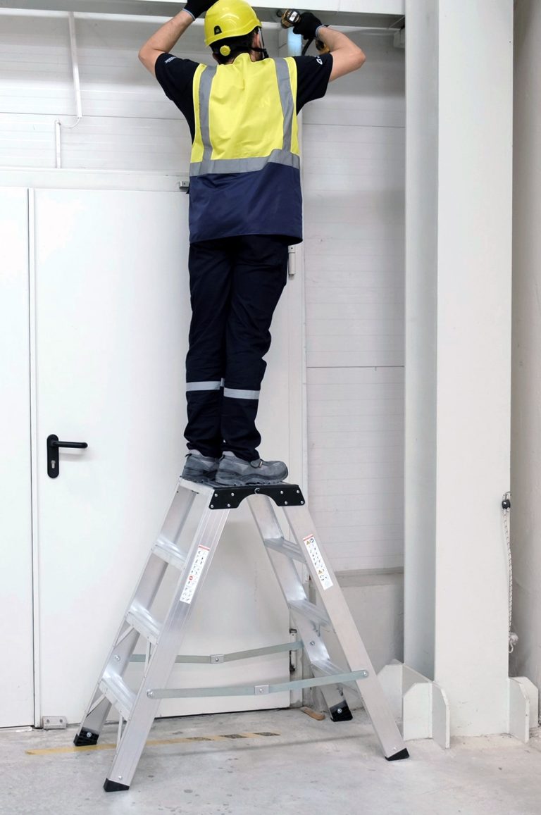 Operario sobre el taburete Kamet reparando unos cables