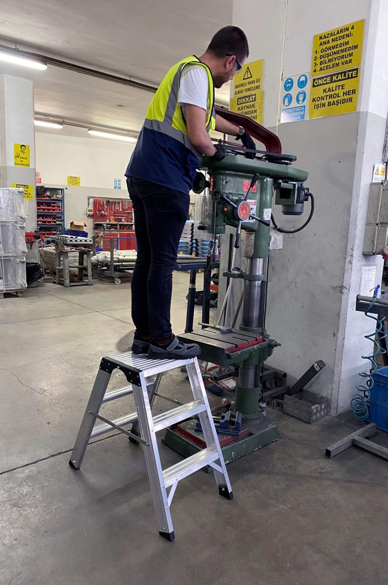 Trabajador sobre el taburete Kamet poniendo a punto una máquina