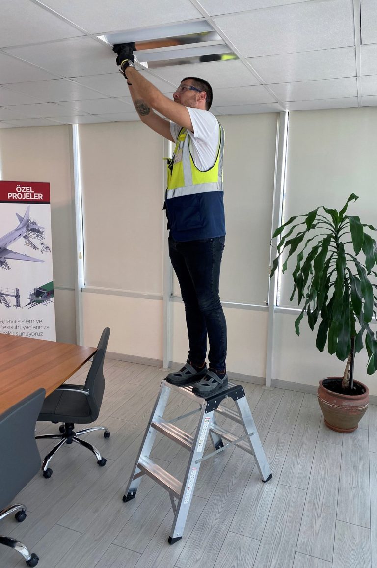 Operario reparando una luminaria sobre el taburete Teide
